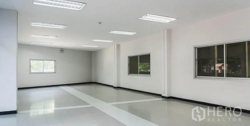 Warehouse for rent in Mueang Samut Sakhon, Samut Sakhon - Bright office room inside the warehouse with tiled flooring, fluorescent lighting, and windows facing greenery.