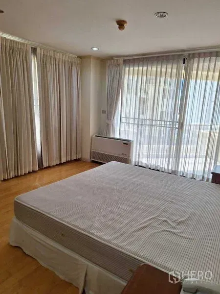 Apartment for rent in Watthana, Bangkok - Corner bedroom with large windows, white curtains and sliding door opening to a balcony.