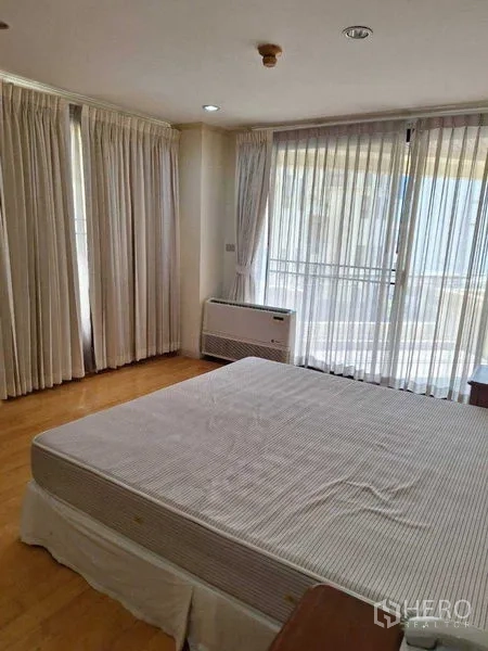 Apartment for rent in Watthana, Bangkok - Corner bedroom with large windows, white curtains and sliding door opening to a balcony.