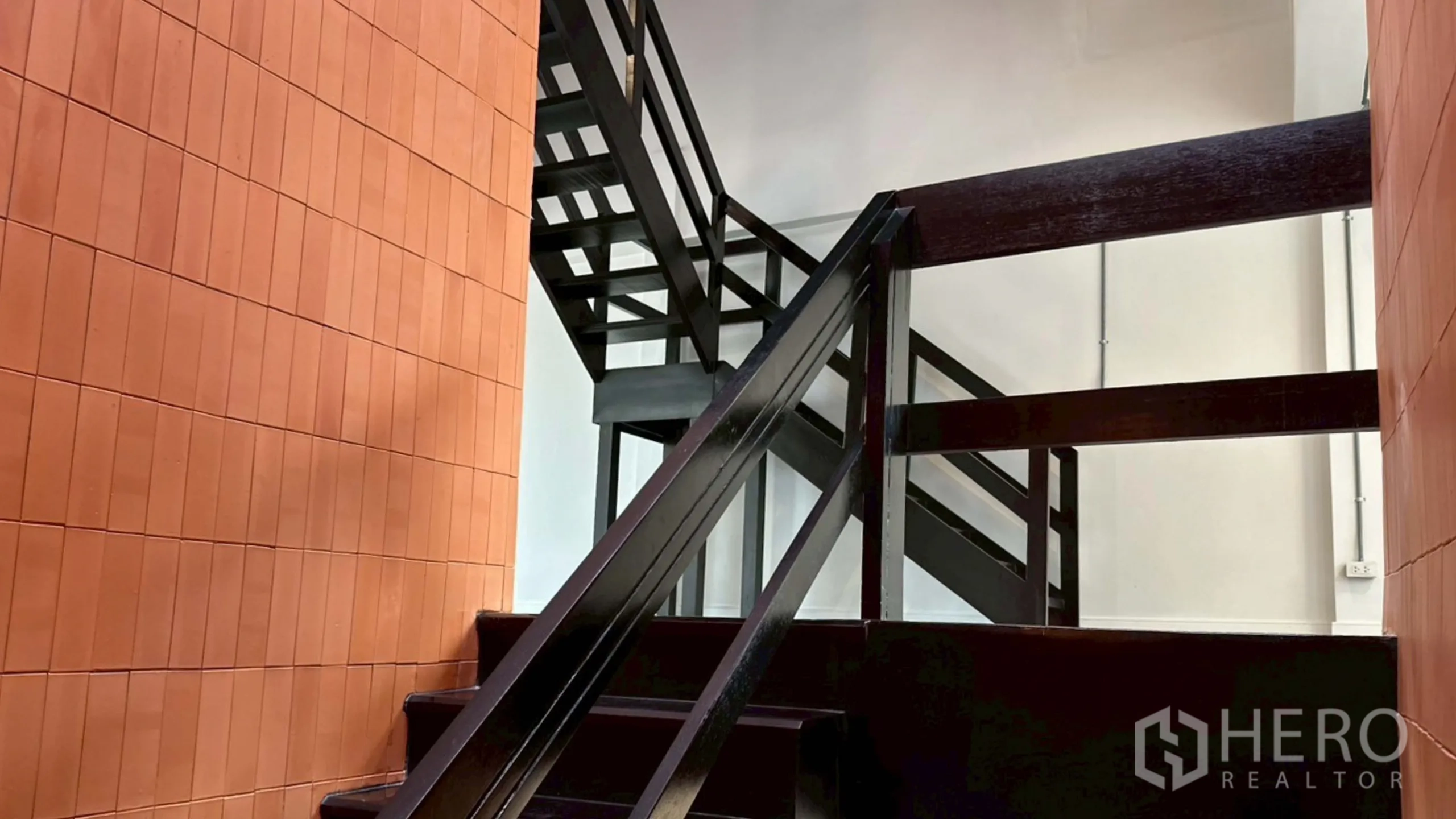 Home Office for rent in Watthana, Bangkok - Black metal stair structure contrasted with terracotta tiles in the core.