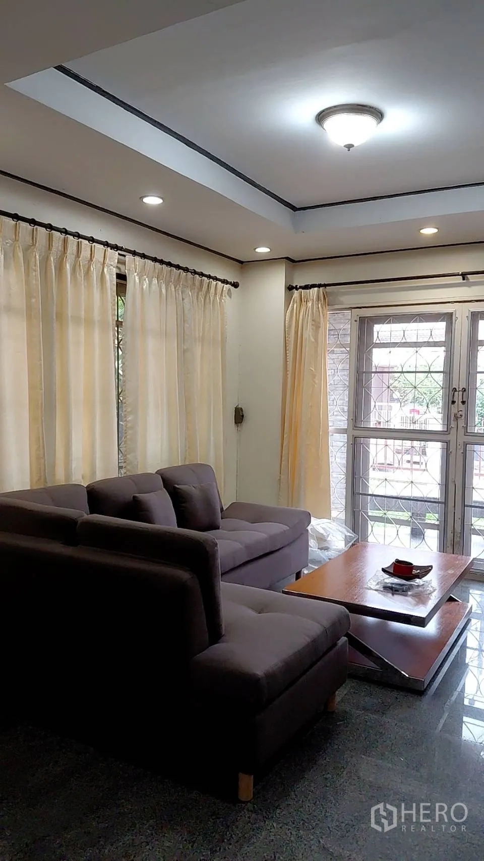 บ้าน ให้เช่าในMin Buri, Bangkok - มุมนั่งเล่นโซฟาเข้ามุม ผ้าม่านโปร่ง และประตูกระจกออกสู่หน้าบ้าน