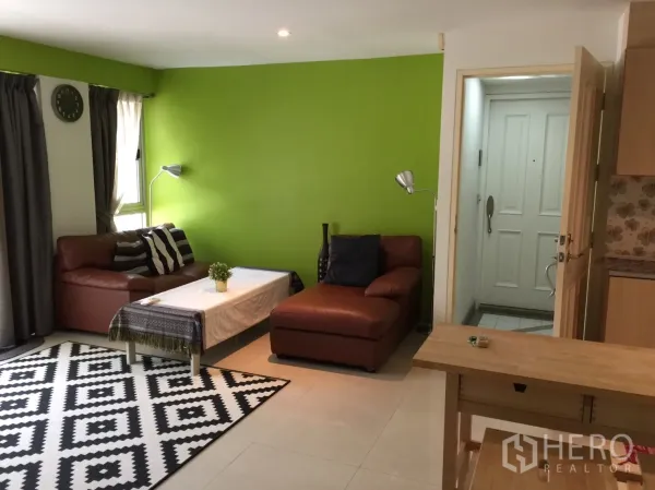 คอนโด ให้เช่าในKhlong Toei, Bangkok - ห้องนั่งเล่นโปร่ง ผนังสีเขียว โซฟาหนังสีน้ำตาล และประตูทางเข้า