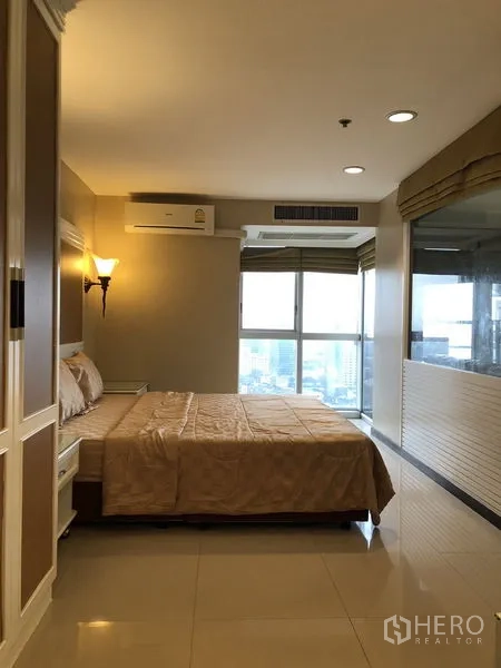 Condominium for rent in Khlong Toei, Bangkok - Bedroom with large windows and access to an enclosed balcony with city view.