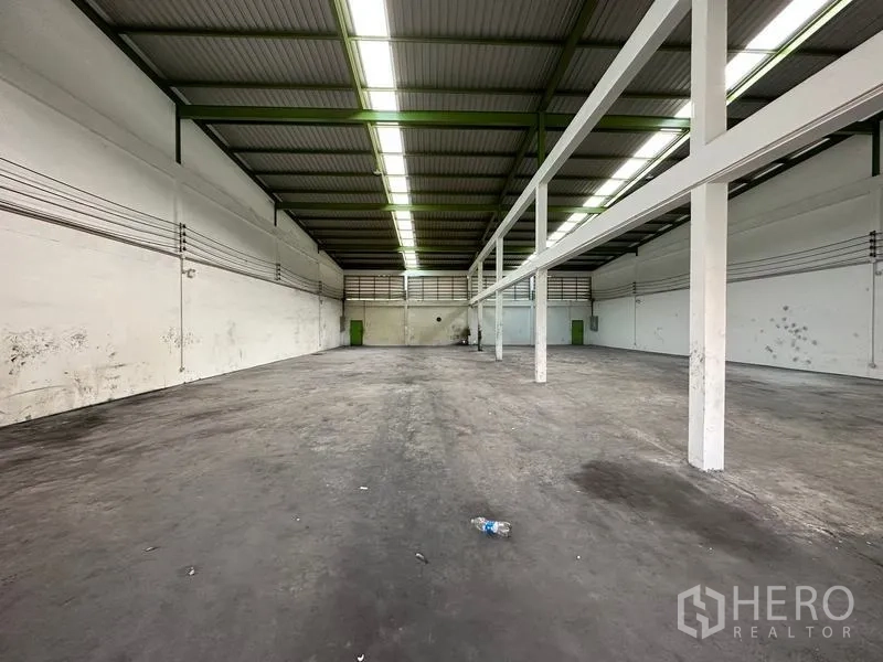 货栈 出租在Pathum Thani - 长条形开放楼层，白色结构梁与明亮线性照明。