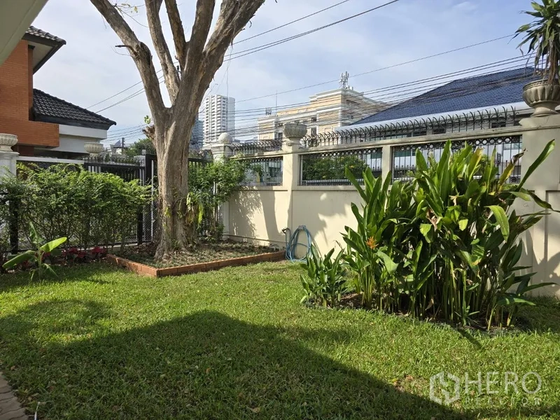 บ้าน ให้เช่าในWatthana, Bangkok - สวนหน้าบ้านมีต้นไม้ใหญ่ พุ่มไม้ และรั้วสูงในบรรยากาศเมืองวัฒนา