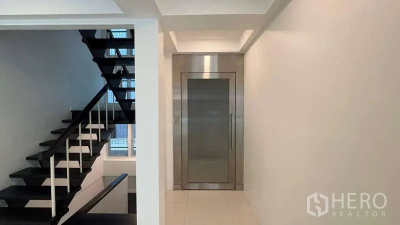 带办公室的家 出租在Khlong Toei, Bangkok - 走廊视角，黑色楼梯旁是不锈钢电梯。