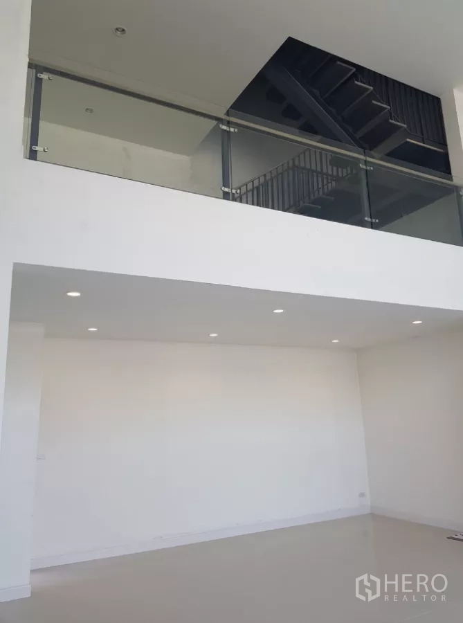 Home Office for rent in Pak Kret, Nonthaburi - Bright double-height interior with a mezzanine level, glass balustrade, and recessed downlights.