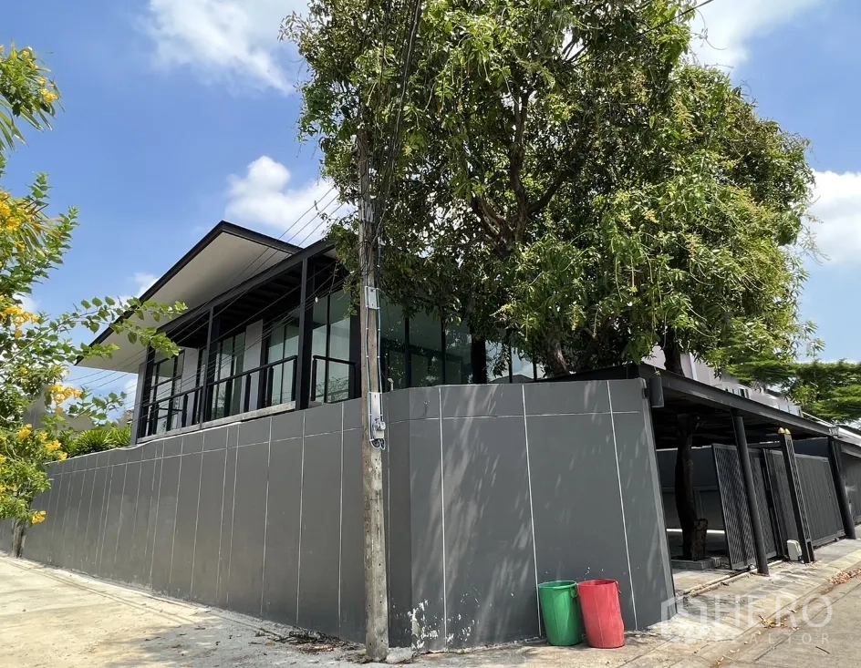 บ้าน ให้เช่าหรือขายในPhra Khanong, Bangkok - ด้านข้างบ้านยกสูง หน้าต่างกระจกเต็มบาน เหนือกำแพงสีเทาบนที่ดินหัวมุม