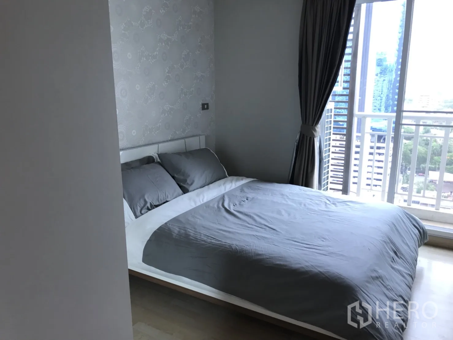 Condominium for rent in Watthana, Bangkok - Second bedroom with grey bedding, floor-to-ceiling window, curtains, and skyline view.