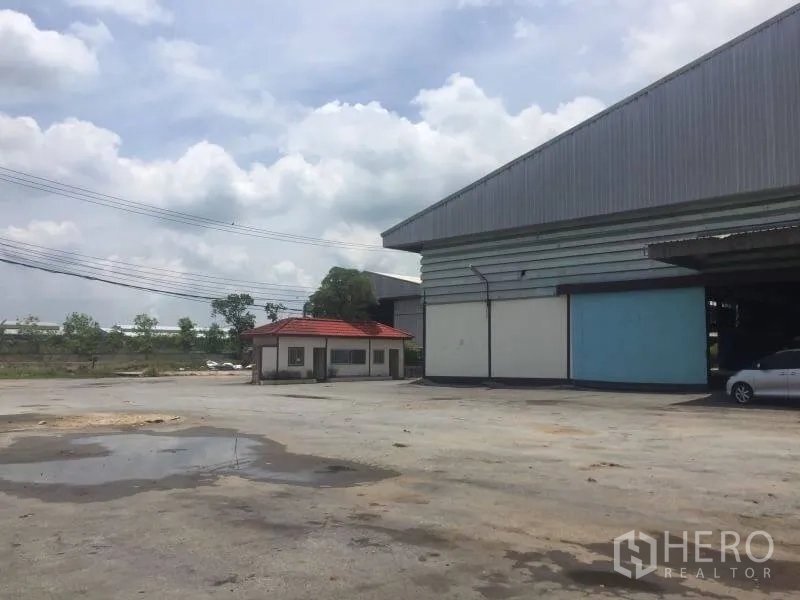 Office Space for rent in Sai Noi, Nonthaburi - Wide concrete yard with a guardhouse and a large metal-clad building in an industrial compound at Sai Noi.