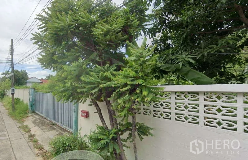 ที่ดิน ขายในLak Si, Bangkok - รั้วรอบแปลงสีขาวพร้อมประตูเหล็กติดซอยเงียบ ร่มรื่นด้วยต้นไม้และสายไฟเหนือศีรษะ