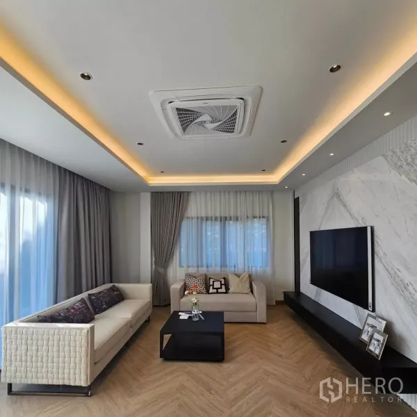 Detached House for rent in Bang Phli, Samut Prakan - Bright living room with marble TV wall, recessed lighting and cassette air conditioner.