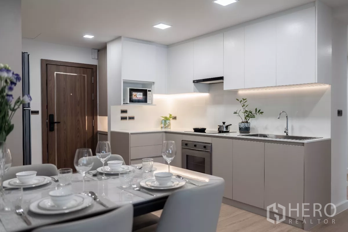 Apartment for rent - Modern kitchen with white cabinetry, built-in oven and microwave, plus a dining table set for four.