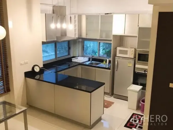 联排别墅 出租在Wang Thonglang, Bangkok - 现代U形厨房，黑色石材台面、不锈钢电器与采光窗。