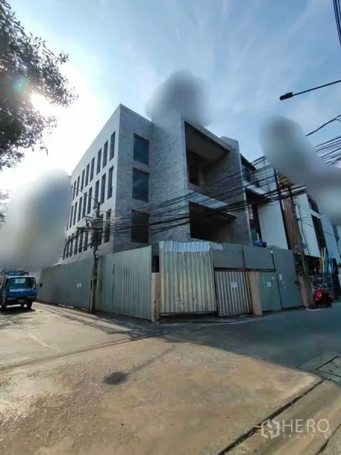 Home Office for rent in Watthana, Bangkok - Street-corner view of a newly built multi-storey home office secured by site fencing.