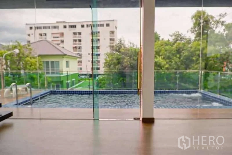 บ้าน ขายในLat Phrao, Bangkok - มุมมองผ่านผนังกระจกออกไปยังสระว่ายน้ำส่วนตัวและอพาร์ตเมนต์โดยรอบ