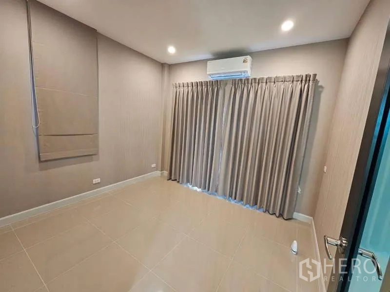 Detached House for rent in Bang Phli, Samut Prakan - Ground-floor room with tiled floor, curtains and wall-mounted air conditioner.