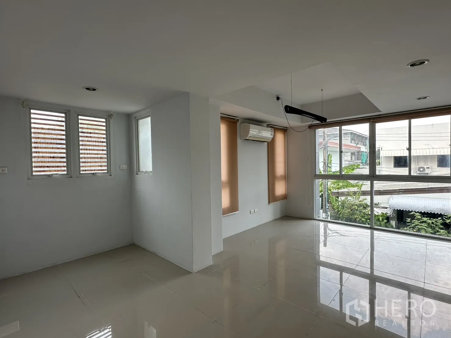 Home Office for rent in Watthana, Bangkok - Open-plan living space with floor-to-ceiling windows and a wall-mounted air conditioner.