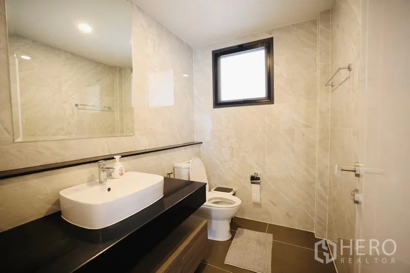 Detached House for rent in Bang Phli, Samut Prakan - Guest bathroom with single vanity, large mirror, and stone-patterned tiles.