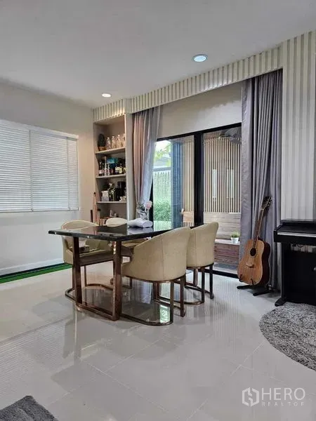 独立式住宅 出售在Khan Na Yao, Bangkok - 采光充足的餐厅，内置置物架，推拉玻璃门通向花园，旁有钢琴。