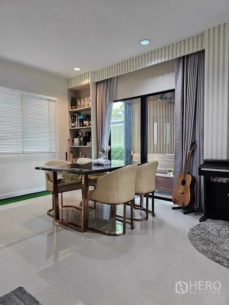 独立式住宅 出售在Khan Na Yao, Bangkok - 采光充足的餐厅，内置置物架，推拉玻璃门通向花园，旁有钢琴。