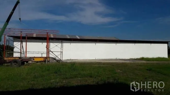 โรงงาน ขายในPhanat Nikhom, Chon Buri - ด้านข้างโกดังยาวผนังสีขาว หลังคาเหล็ก พร้อมเครนในพื้นที่