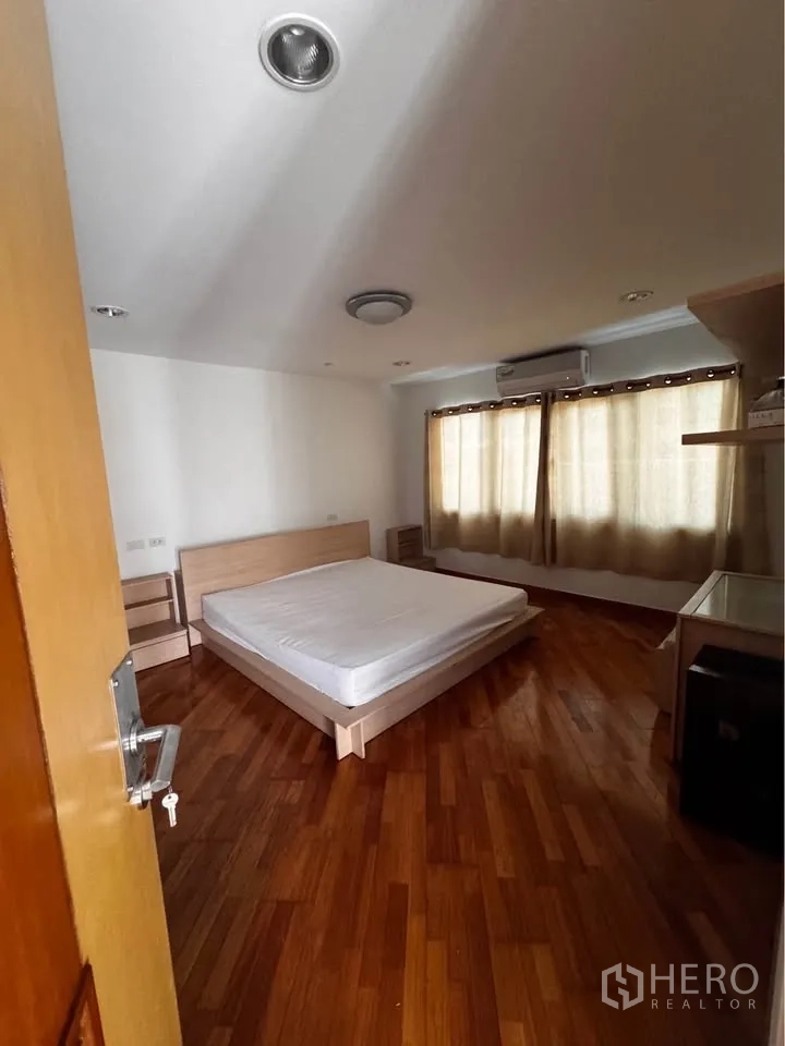 ทาวน์เฮาส์ for rent in Huai Khwang, Bangkok - ห้องนอนเฟอร์นิเจอร์ลายไม้สีอ่อนและผ้าม่าน.