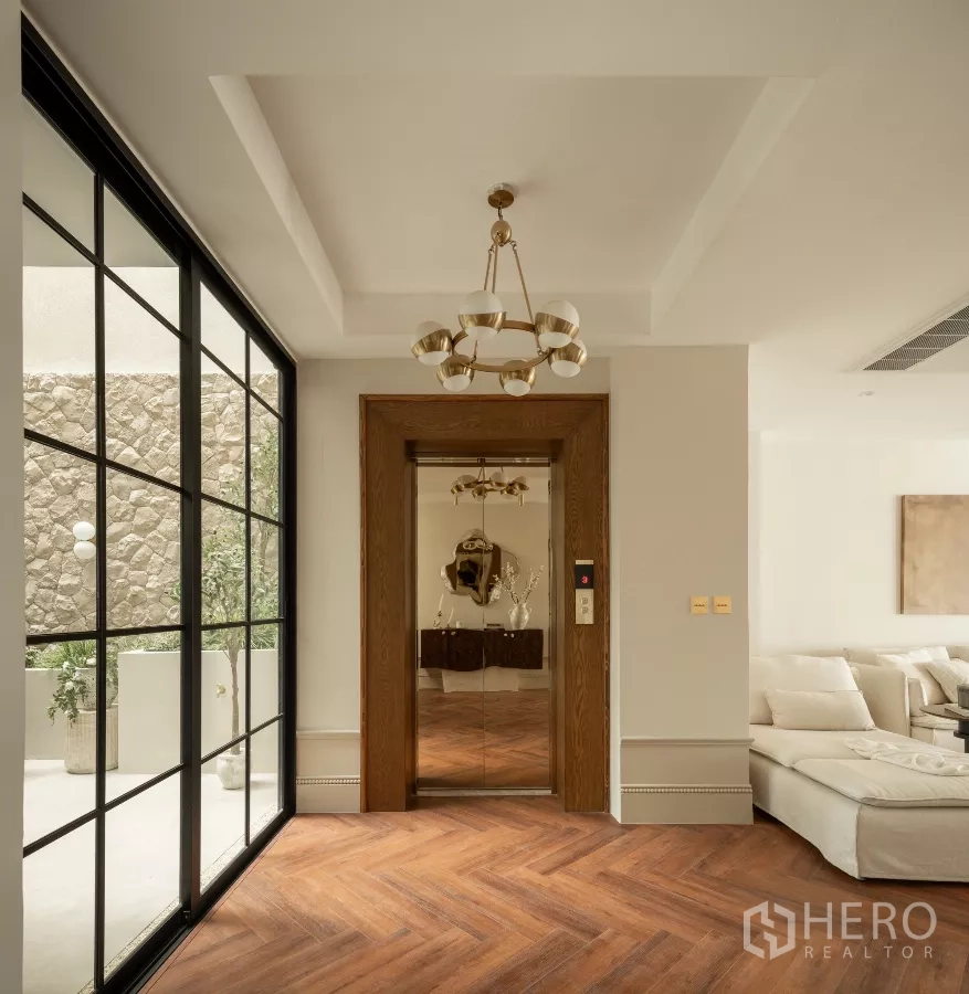 带办公室的家 出售在Phra Khanong, Bangkok - 电梯前厅，黄铜吊灯、镜面电梯与人字拼地板。