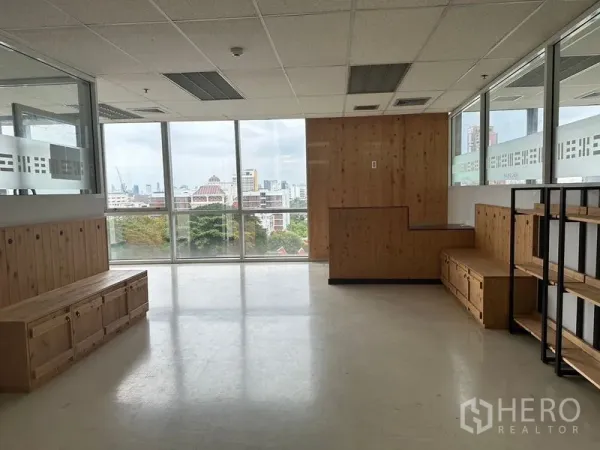 สำนักงาน ให้เช่า - มุมรอรับในสำนักงาน มีม้านั่งไม้ ชั้นวาง และวิวสกายไลน์ผ่านหน้าต่างบานใหญ่