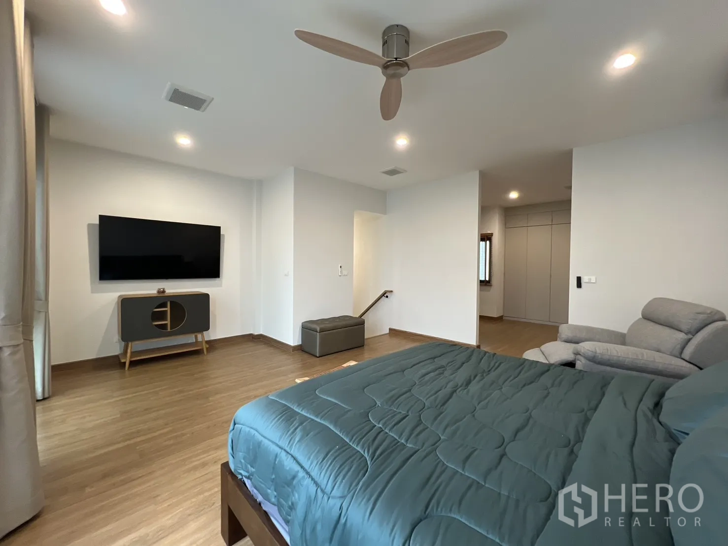 Detached House for rent in Prawet, Bangkok - Expansive master bedroom with TV, seating and wood floors.