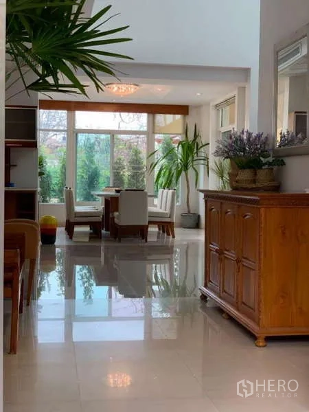 独立式住宅 出租在Lat Krabang, Bangkok - 走廊通往餐区，亮面地砖与绿植点缀。