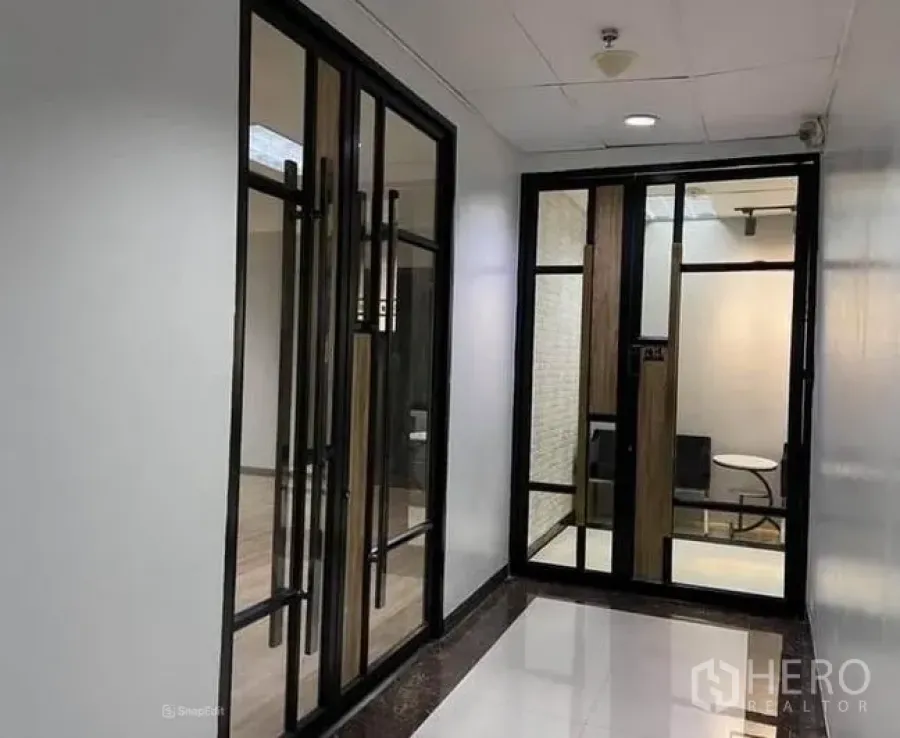 办公空间 出租在Bang Na, Bangkok - 现代办公套间入口，黑色金属框玻璃双门与明亮走廊，位于邦纳。