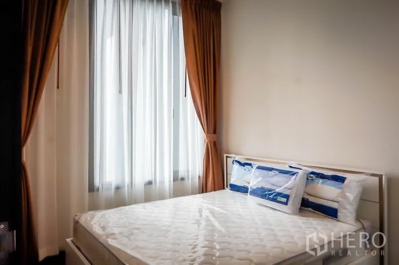 Condominium for sale in Watthana, Bangkok - Cozy bedroom with double bed, large windows and blackout curtains.