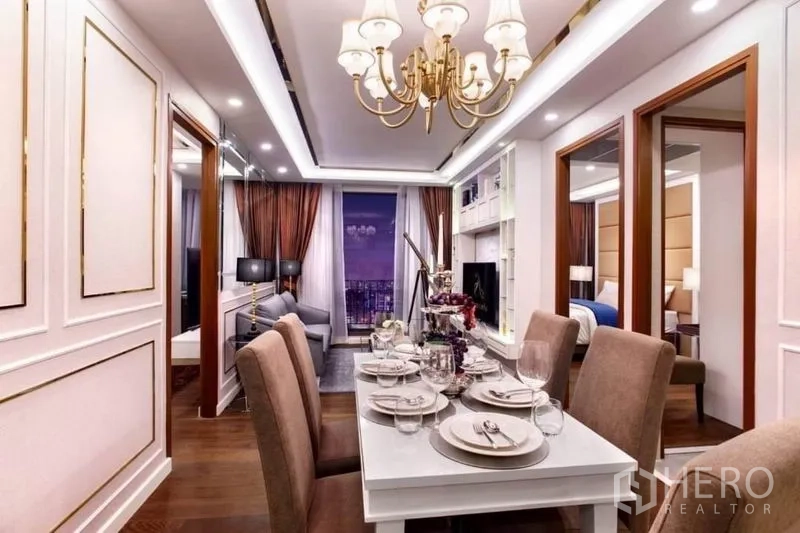 Condominium for rent in Huai Khwang, Bangkok - Open-plan dining and living space with chandelier, two bedroom entrances and city view beyond.