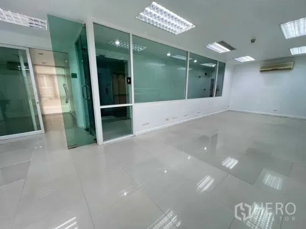 Office Space for rent in Wang Thonglang, Bangkok - Bright workspace facing glass meeting rooms with frosted panels and overhead fluorescent lighting.