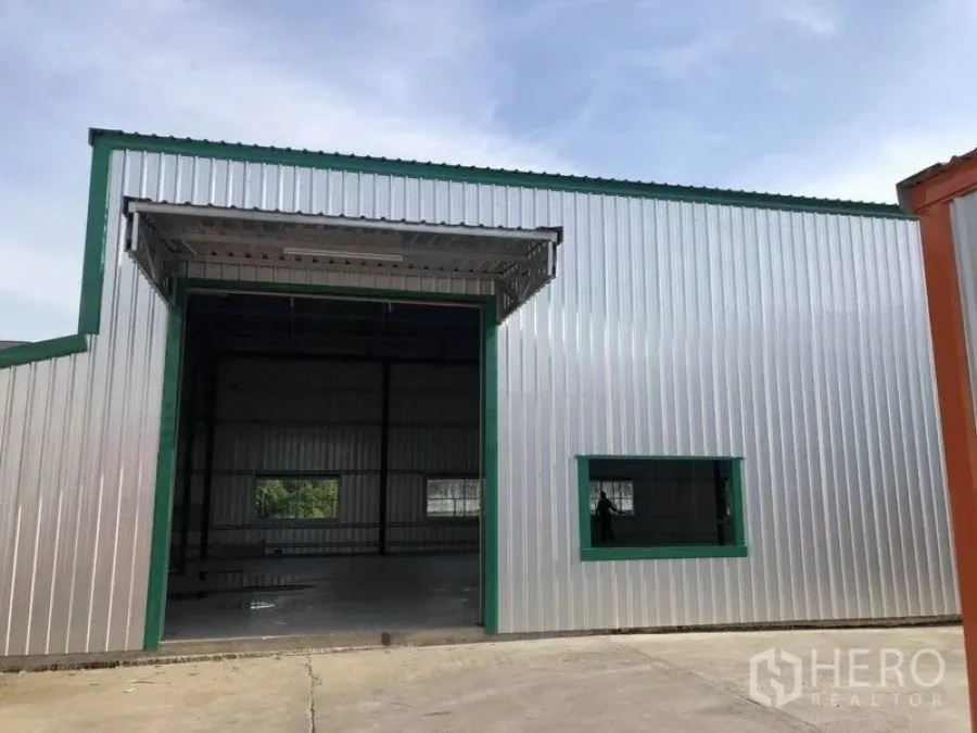Warehouse for rent in Nonthaburi - Warehouse facade with large roller shutter loading door, window and paved apron.