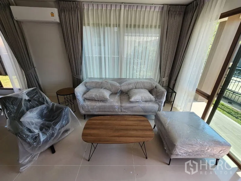 Detached House for rent in Bang Kapi, Bangkok - Sofa set and coffee table wrapped for move-in beside floor-to-ceiling windows.