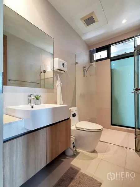 公寓 出租在Sathon, Bangkok - 卫浴带玻璃淋浴间，悬挂式浴柜与明亮瓷砖。