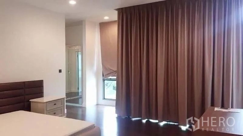 Detached House for rent in Bang Kapi, Bangkok - Bedroom with blackout curtains and a doorway to the en-suite shower room.