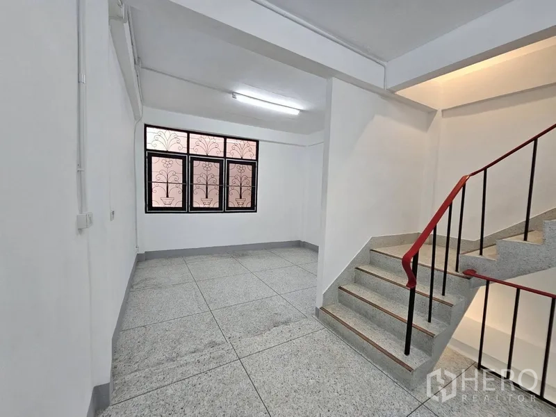 店屋 出租 - 楼梯平台，红色扶手与花纹铁艺窗。