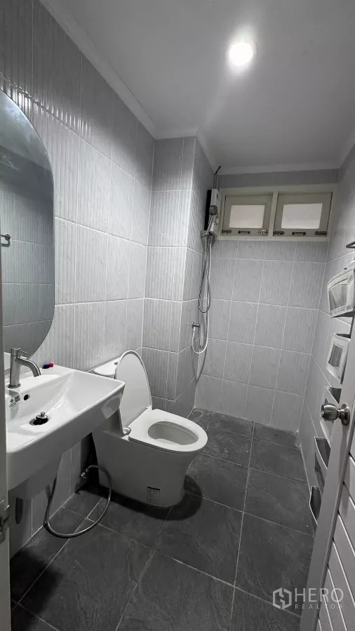 บ้าน ให้เช่าในLat Krabang, Bangkok - ห้องน้ำกรุผนังกระเบื้องสีเทา พร้อมอ่างล้างหน้า โถสุขภัณฑ์ และฝักบัว