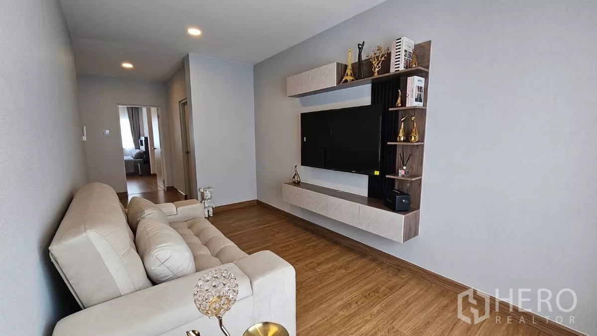 Detached House for rent or sale in Bang Phli, Samut Prakan - Upstairs family room with tufted sofa, wall-mounted TV and display shelving on wood flooring.