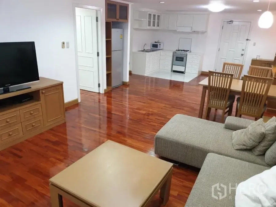 คอนโด ให้เช่าในWatthana, Bangkok - ห้องนั่งเล่นและทานอาหารแบบเปิด พื้นไม้จริง โซฟา ทีวี และครัวขนาดกะทัดรัดที่ Acadamia Grand Tower ใกล้ BTS พร้อมพงษ์