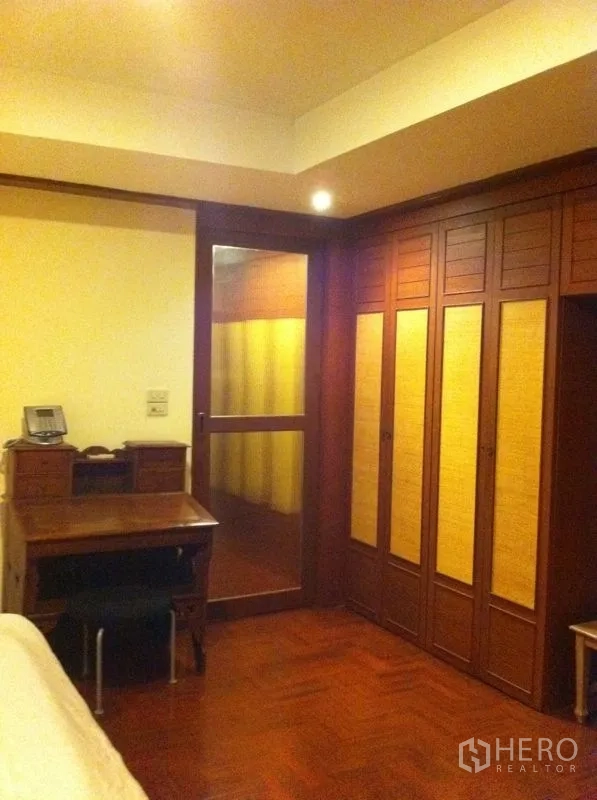 Townhouse for rent or sale in Watthana, Bangkok - Bedroom with built-in wardrobes, study desk and parquet flooring.
