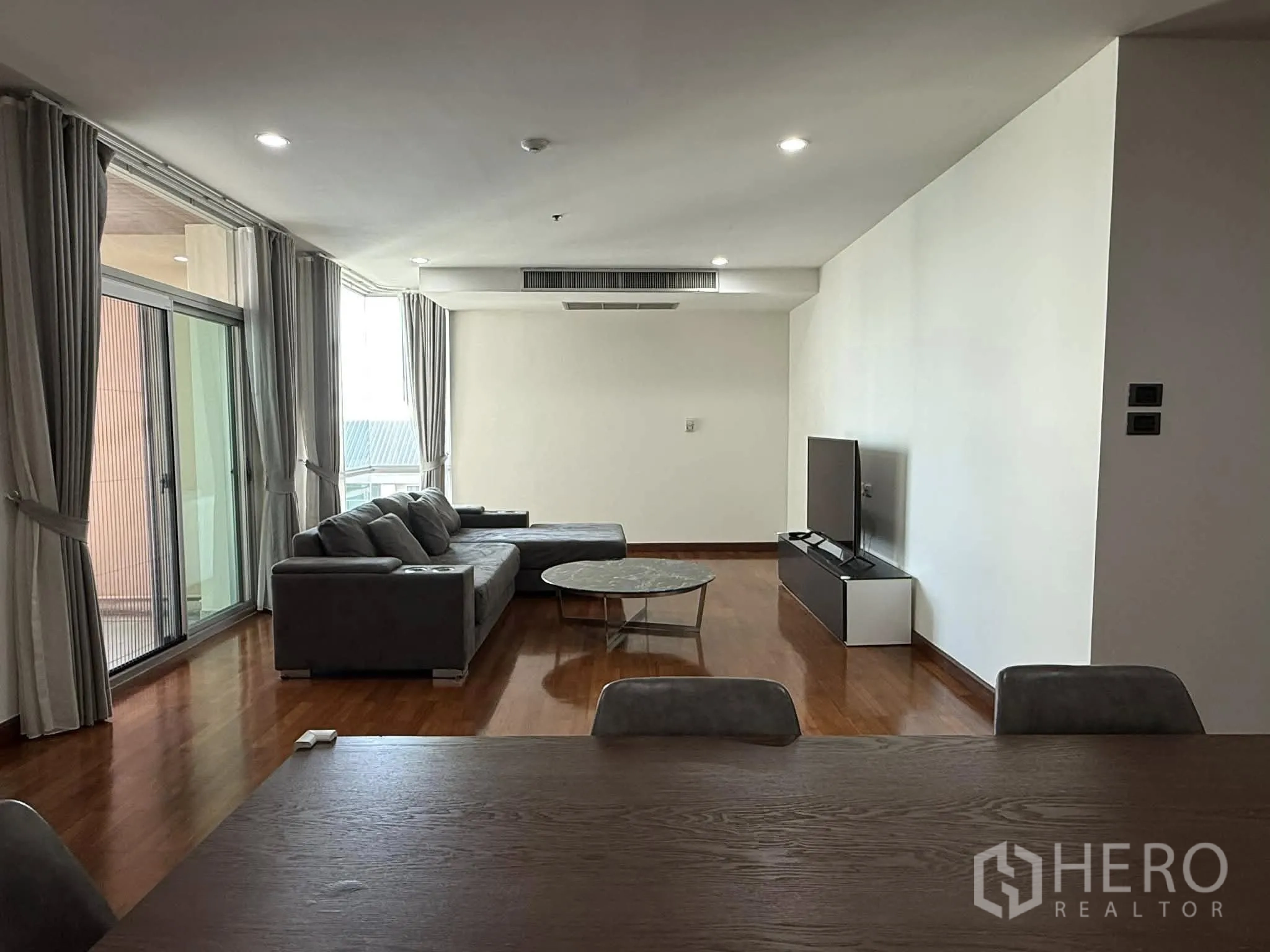 公寓 for rent in Pathum Wan, Bangkok - 客厅带推拉玻璃门通向阳台，长窗帘与筒灯照明。