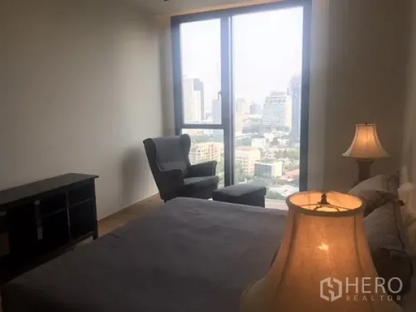 公寓 出租或出售在Khlong Toei, Bangkok - 卧室设落地窗与休闲椅，远眺城市天际线