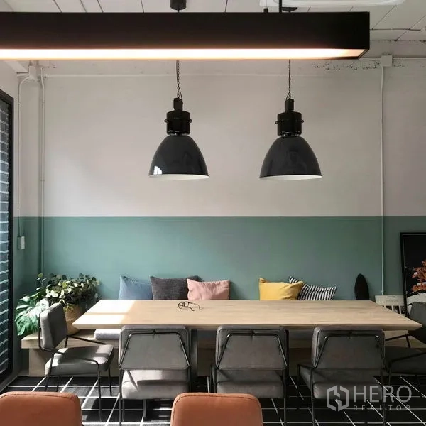 Townhouse for rent or sale in Khlong Toei, Bangkok - Dining area with long wooden table, industrial pendant lamps and soft cushions.