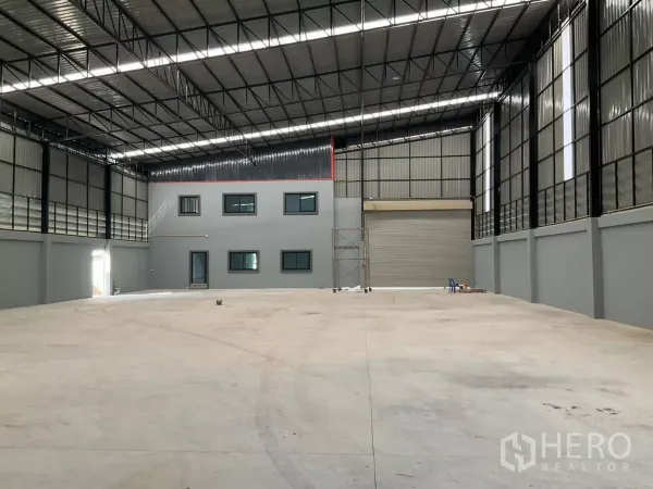 工厂 出售在Samut Sakhon - 厂房内部，高挑无柱钢结构屋顶、卷帘门与平整地坪