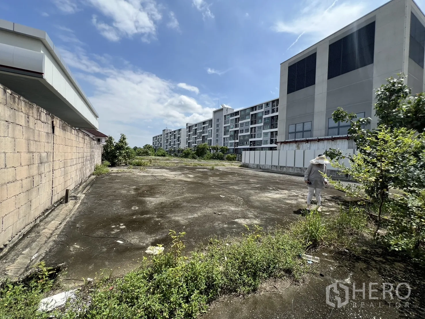 Land for sale in Bang Kapi, Bangkok - Back section of the site near modern low-rise buildings with a boundary wall and trees.