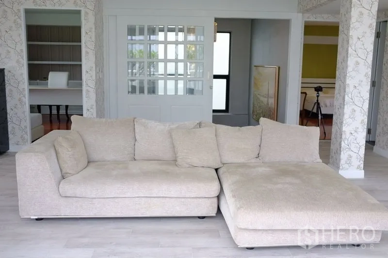 公寓 出租在Watthana, Bangkok - 采光充足的家庭厅，米色L型沙发与推拉玻璃门。